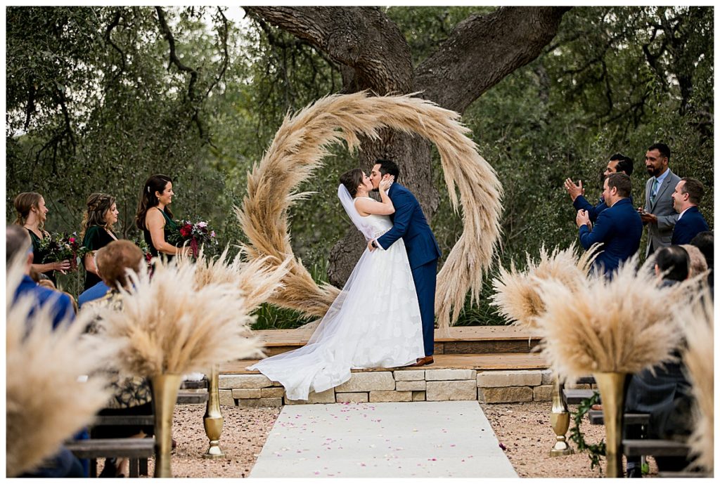 bride and groom ceremony kiss with pampas grass arch