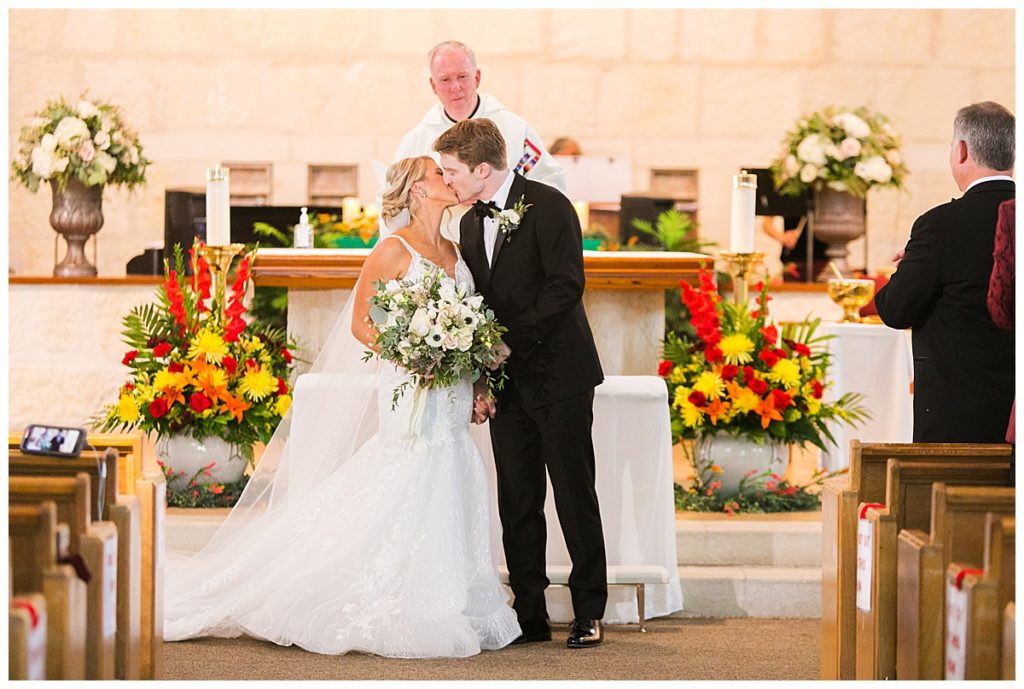 bride and groom kiss at ceremony in church