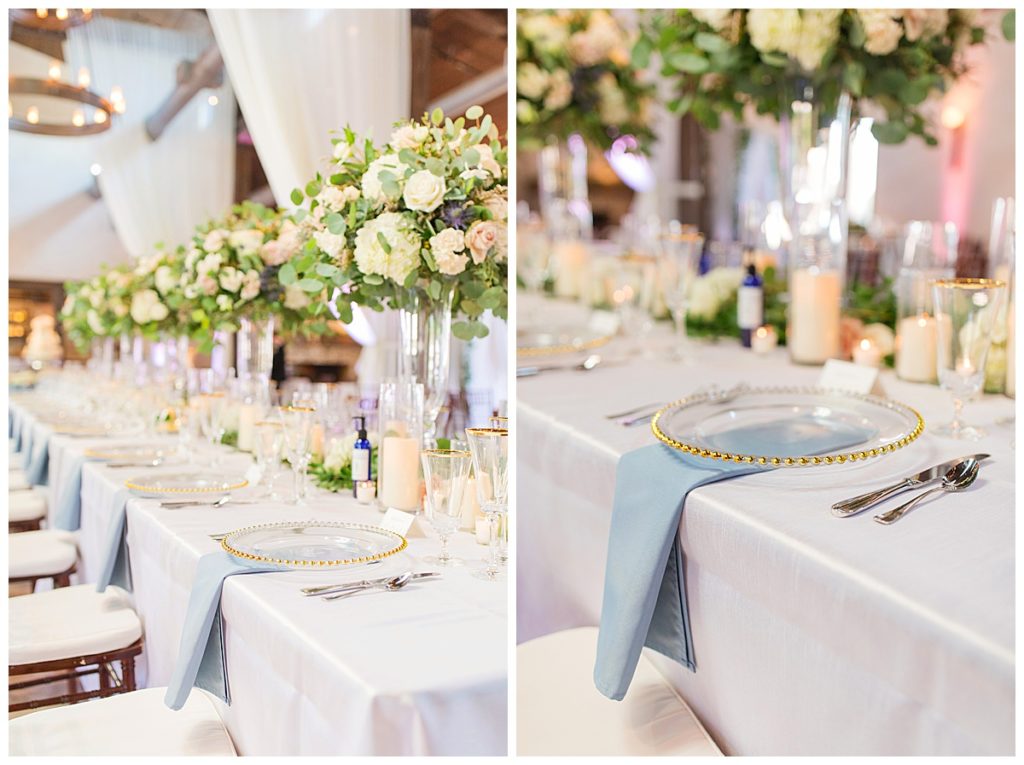 head table decorated with tall flower arrangements and silverware and blue napkins