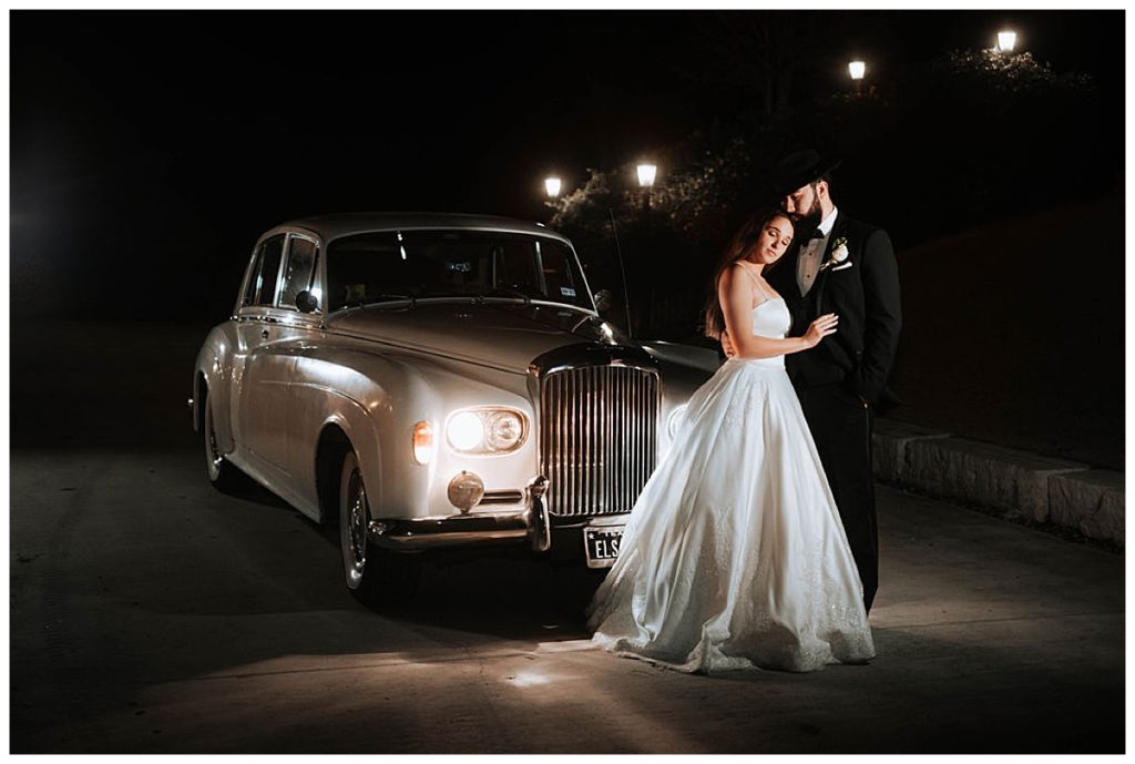 bride and groom in front of classic getaway car 