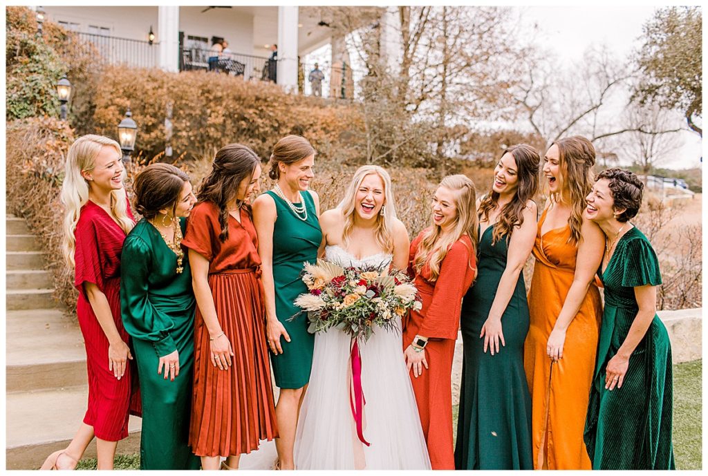 bride with standing with bridesmaids in colorful jewel tone dresses