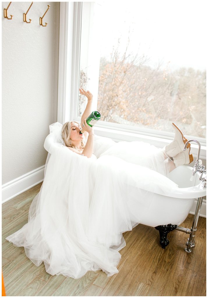 bride drinking champagne in bathtub wearing wedding dress