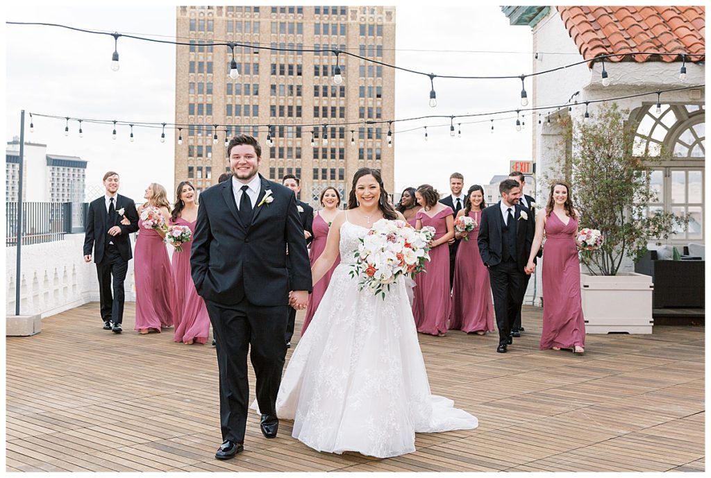 bride and groom pose with bridal party on rooftop