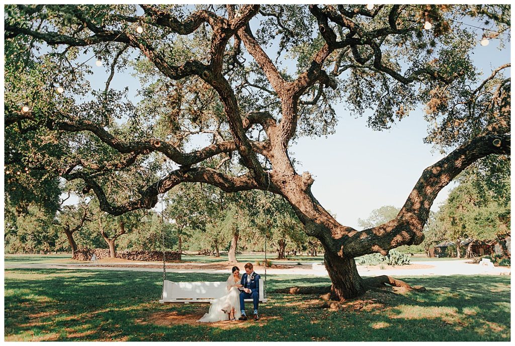 bride and groom share intimate moment on swing under a large oak tree