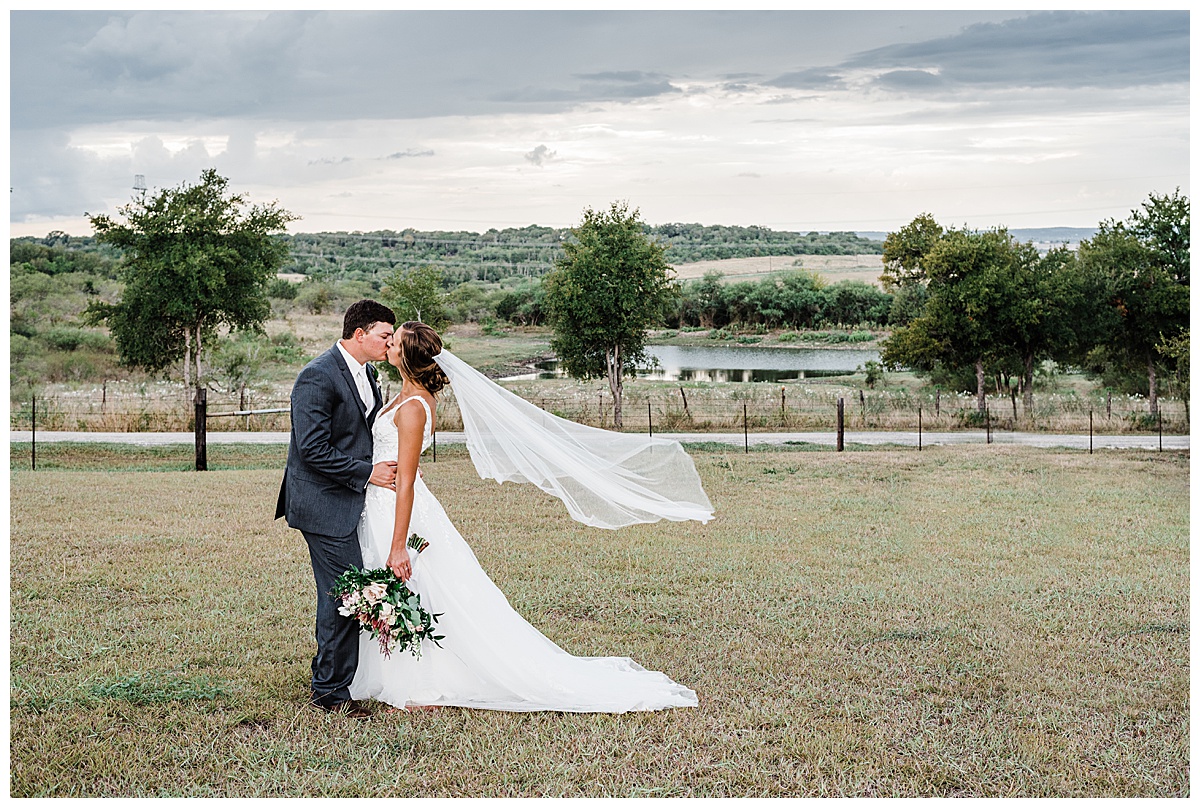 bride and groom kiss in field in texas