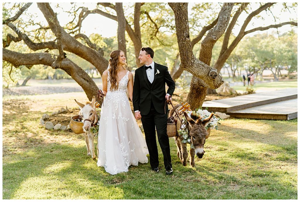 bride and groom standing with beer burros in front of tree